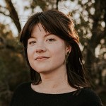 Erin Berger has shoulder-length auburn hair with bangs and is looking at the camera