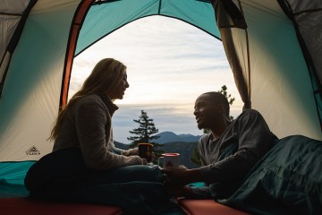Two people chat inside a tent.