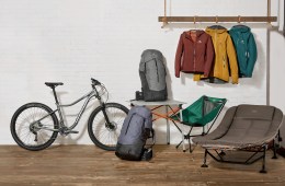 Editorial photo of various gear, including a bike, jackets and two packs.