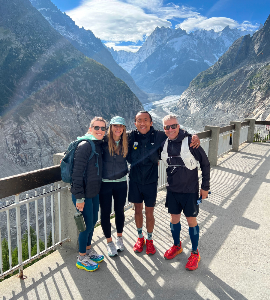 Four people pose smiling in front of a mountain view together.