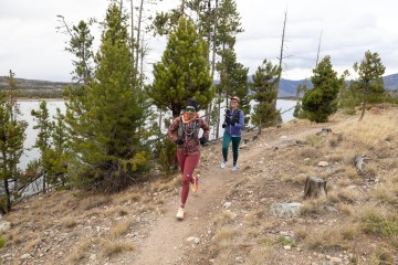 Two people running in cold-weather running gear, including running tights, half-zip sweaters and hydration vests.