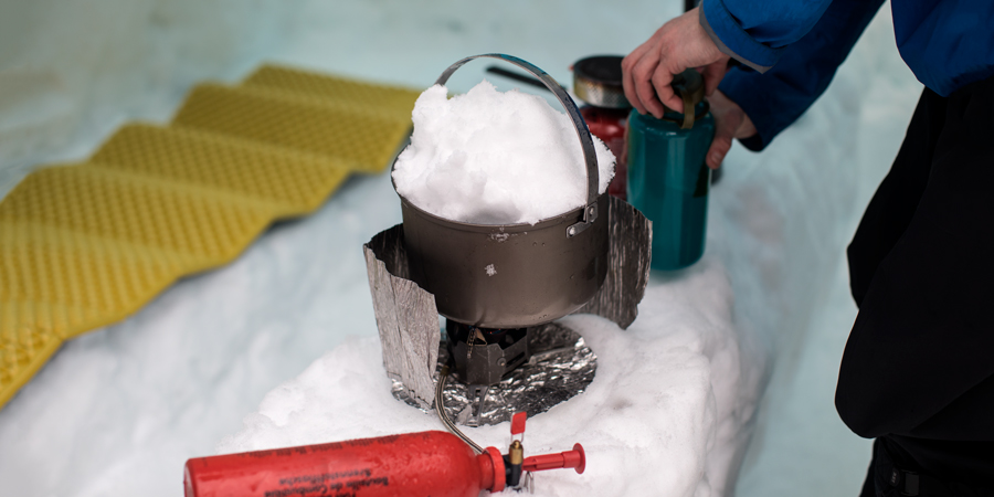 Photo of someone melting snow on a camp stove.