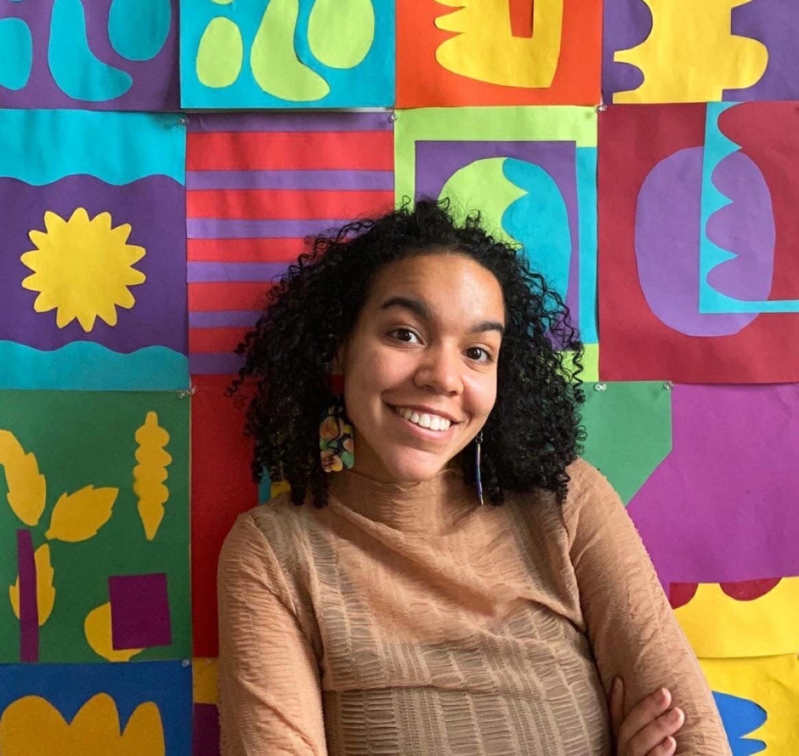 Chelsea Alexander stands in front of a colorful textile that she designed