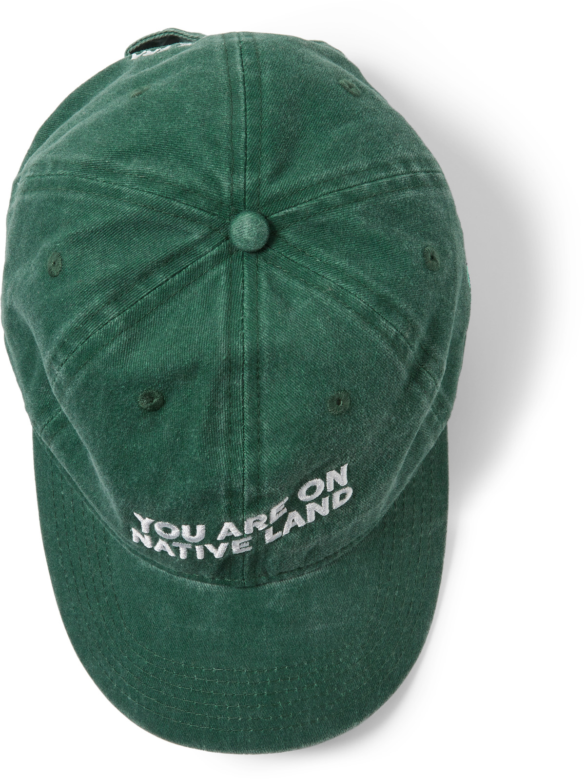 A green hat with "You Are On Native Land" embroidered on it, as seen from above,