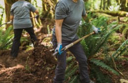 Two people use garden tools to work on a trail.