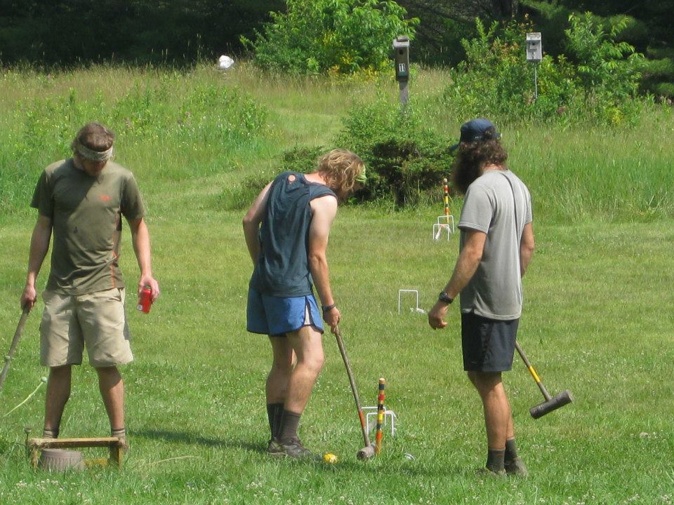 Three hikers play a lawn game on a break from the AT.