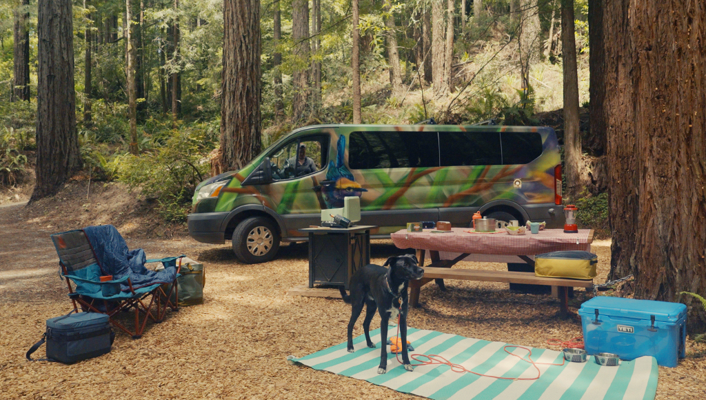 Photo of a camper van at a forest campsite.