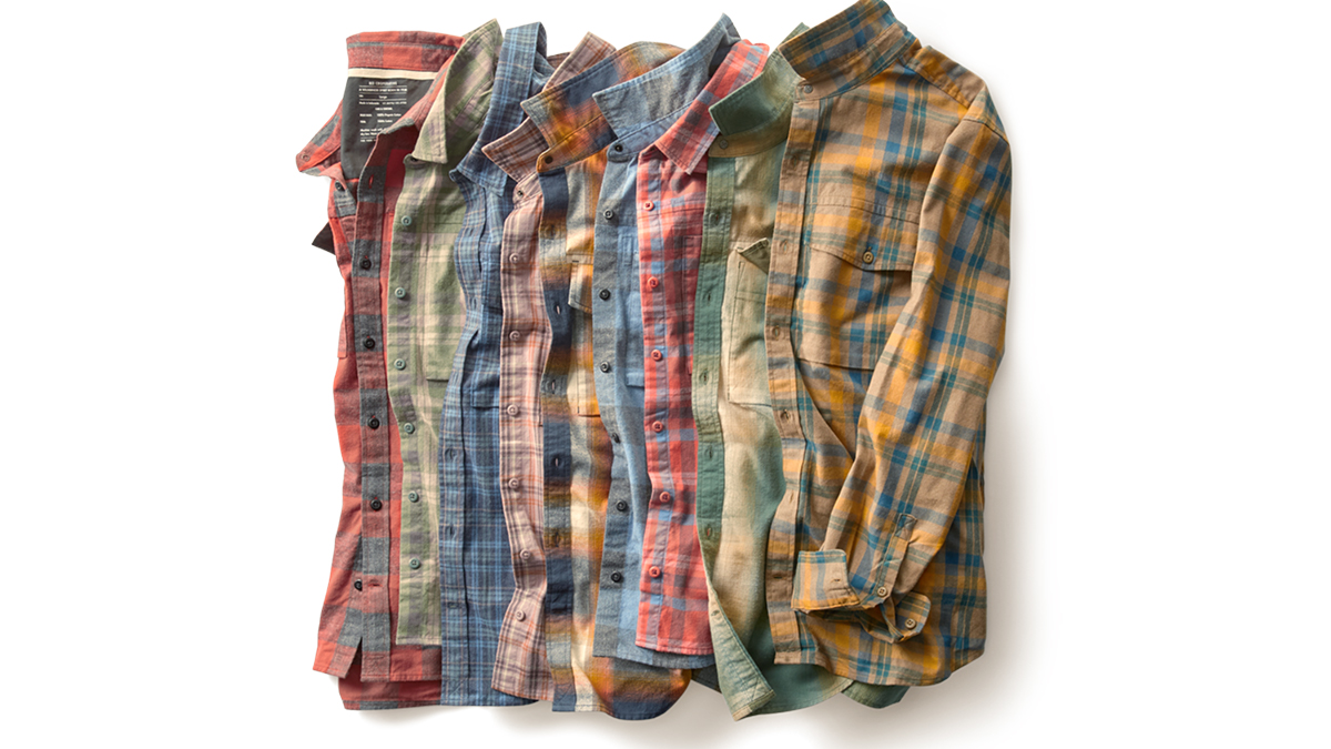 A row of differently colored flannel shirts, folded in half and stacked on each other