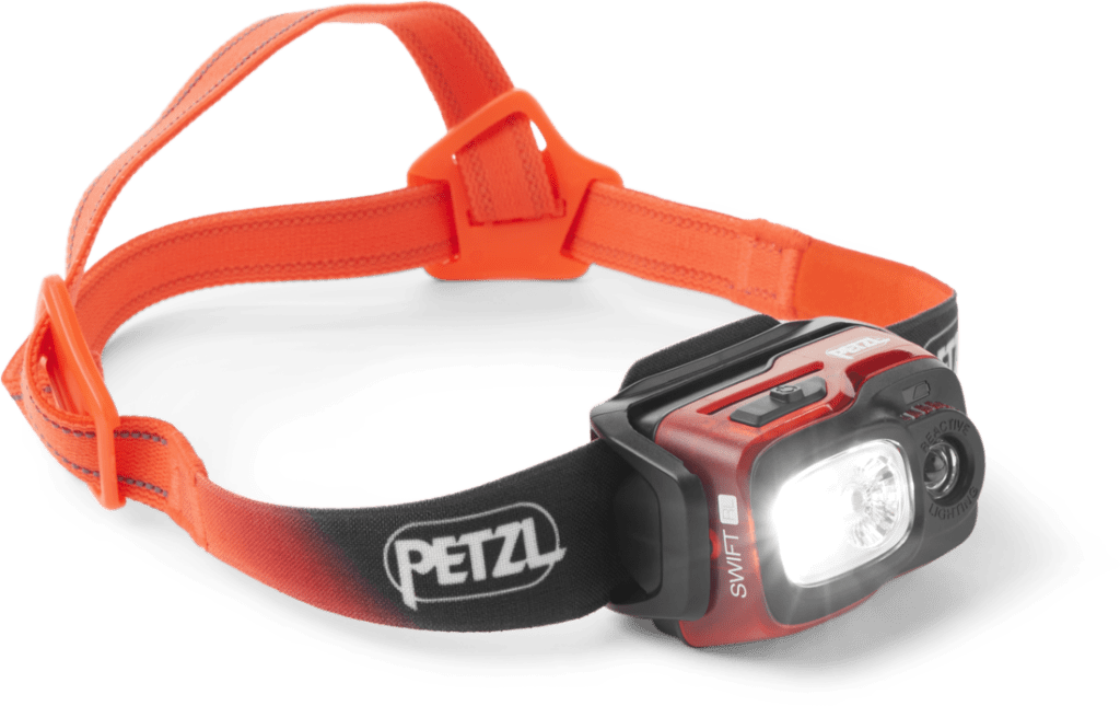 An illuminated headlamp with an orange head strap.