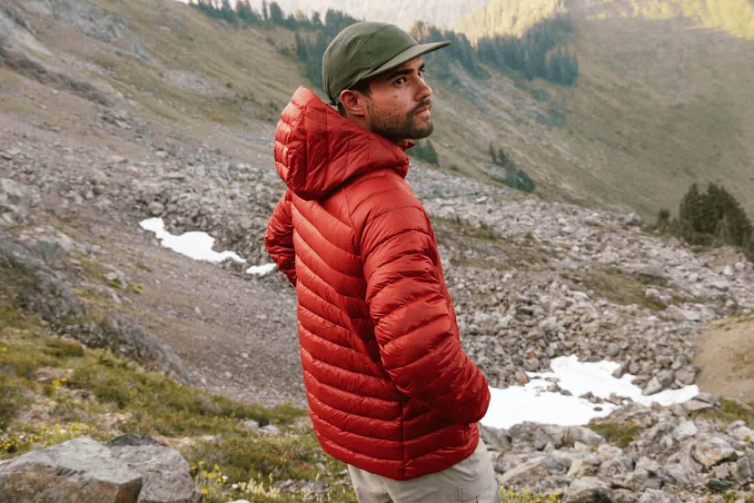 A person wearing a green hat and a red down jacket looks off camera