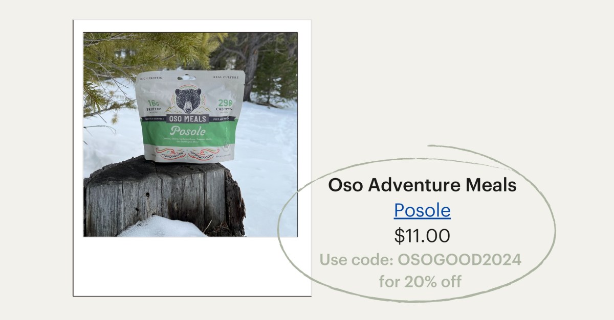 A pouch of Posole backpacking food from the brand Oso Adventure Meals sits on a wood stump in a snowy setting. $11.