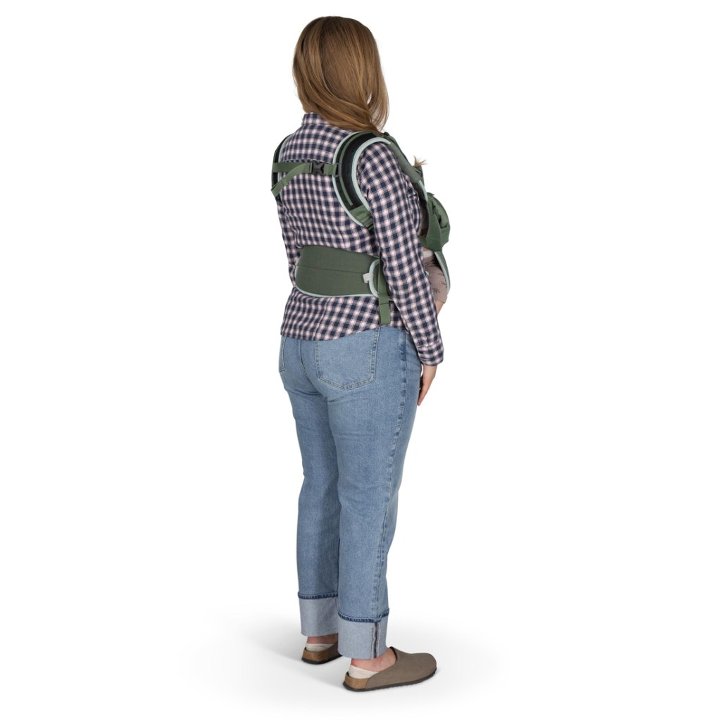 A person is wearing a soft child carrier with the child in the forward position, facing inward