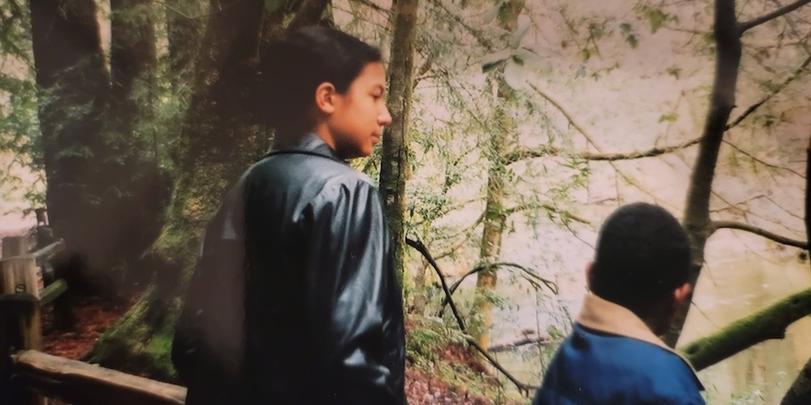 Lestarya Molloy, as a young girl, stands in a forested area and looks at a body of water.