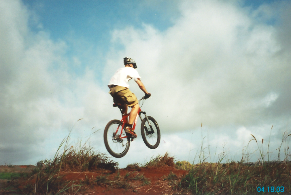 A mountain biker soars above the ground on a jump
