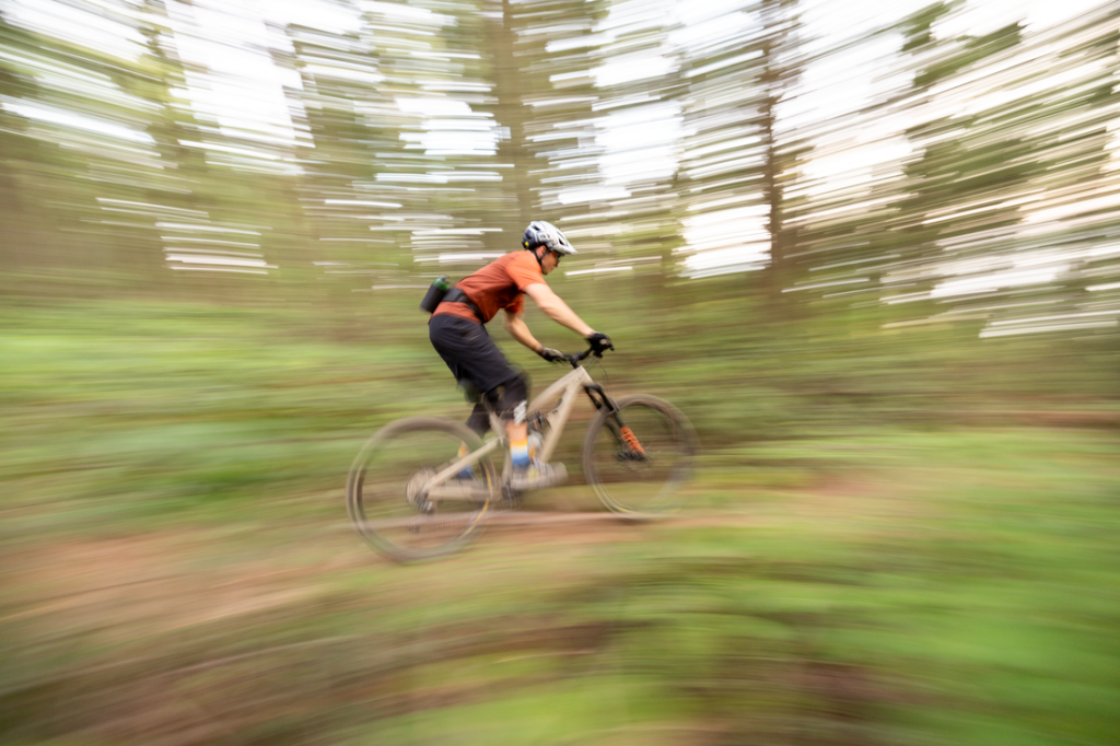 A mountain biker zooming through the woods on a trail