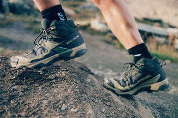 A close-up of a person's boots as they scale a boulder.