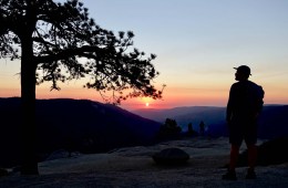 A person in silhouette watches a sunset