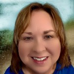 A close-up of a person in a blue shirt smiling at the camera