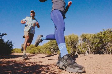 Two people running on a trail in the HOKA Challenger 8 trail-running shoes in black.